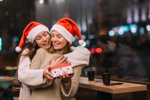 The girl gives a gift to her female friend in caffe photo