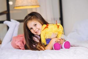 little girl with a toy on the bed photo