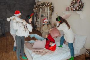 Multi-ethnic friends have fun fighting on pillows on new year's eve photo