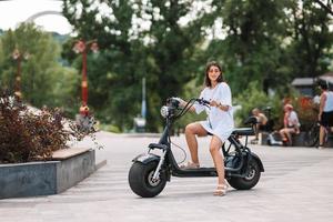Young beautiful woman and an electric scooter, ecological transport photo