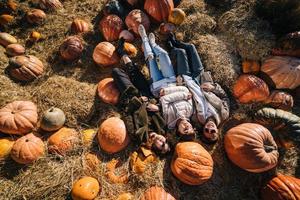 Young girls lie on haystacks among pumpkins. View from above photo