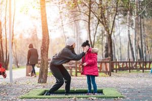 mamá y su hija saltando juntas en trampolín en el parque de otoño foto