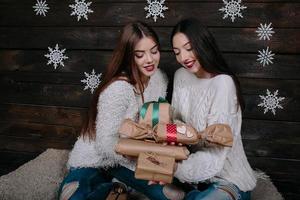 Two beautiful girls offer gifts to camera photo