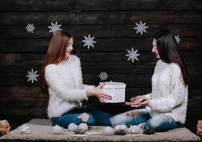 Two young girls holding bright holiday present photo