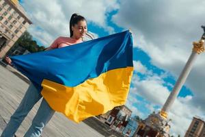 mujer joven con bandera nacional de ucrania en la calle foto