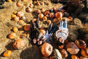 Young girls lie on haystacks among pumpkins. View from above photo