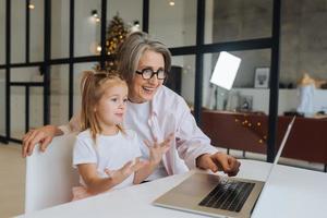 Child and granny looking at the camera with laptop photo