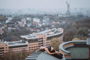 Woman practicing yoga on the roof and doing yoga exercises photo