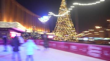 People enjoy ice skating in the street around Christmas tree in rink. photo