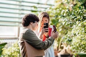 Young agricultural engineers taking photos on a smartphone in greenhouse