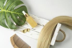 A natural essential oil or serum for hair care in golden capsules lying on a white table. Hair care and smoothing concept photo