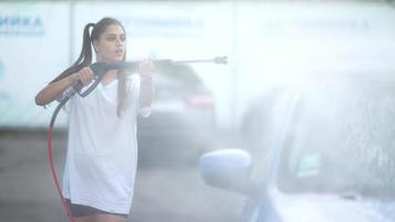 mujer joven lavando un auto azul en un lavadero de autos foto