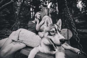 beautiful couple together with dog on a swing photo