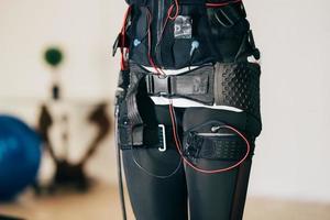 EMS training. Girl doing exercises in a suit with cables. photo