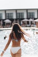 mujer joven en el fondo de la piscina en traje de baño blanco. foto