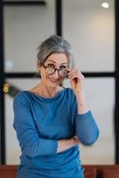 Elderly woman smiles and looking at the camera through glasses photo