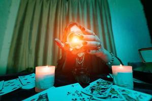 Woman fortune-teller guesses fate of night at table with candles photo