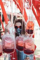 Girl in sunglasses, mask posing among empty bags with blood. photo