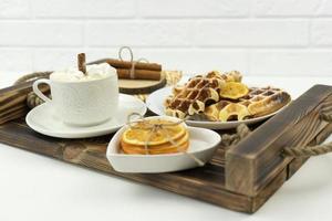 Early breakfast coffee with marshmallows and a stick of cinnamon and Belgian waffles lie on a wooden tray photo