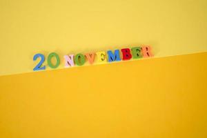 November 20 on a yellow and paper background with wooden and multicolored letters with space for text. photo