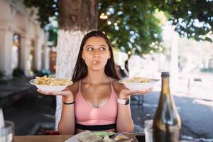 Young women hold french fries on white plates. Street cafe photo