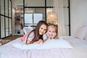 dos niñas acostadas en la cama y mirando a la cámara. foto