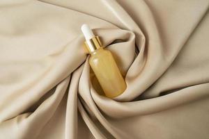A vitamin C serum or natural essential oil lying on a beige fabric photo