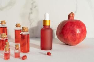 Red dropper bottles of pomegranate serum or oil for face and body standing on a white background photo