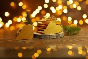 Two golden hearts lie on a wooden table with bokeh lights on the background photo