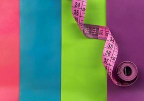 A pink measuring tape lies on the colorful fitness elastic bands photo