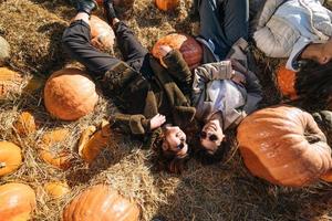 Young girls lie on haystacks among pumpkins. View from above photo