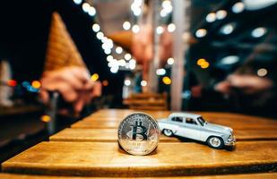 Silver bitcoin and Moskvich 401 on the table, glowing background photo