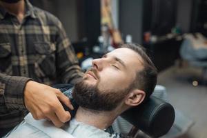 Barber preparing man face for shaving with hot towel in barber shop photo
