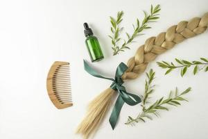 Natural blonde hair tress and essential oil for hair treatment in golden capsules lying on a white background photo