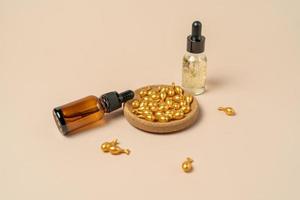 A face serum or oil in golden capsules lying on a beige background photo