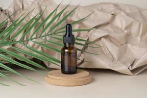 A CBD face serum or oil in a brown dropper bottle with a green leaf beside it on a craft paper background photo