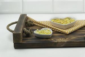 Yellow capsules of Omega 3 lie on white ceramic plates in the form of the hearts on a wooden tray photo