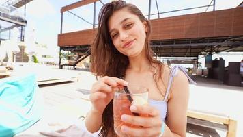 Pretty woman in bikini drinking cocktail at pool party. photo