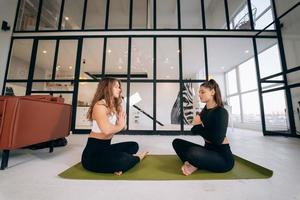 Two young women meditating in lotus pose with hands in namaste. photo