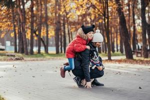 Happy mother and her daughter playing with dog in autumn park photo