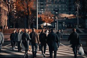 Lots of people crossing the street at the traffic lights. photo