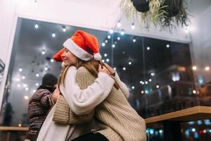 Portrait of happy cute young friends hugging each other at caffe. photo