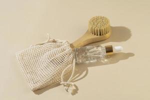 A transparent natural organic serum or essential oil for face care and face  massaging brush lying on a beige background photo