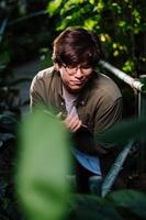 Male scientist hiding in the thicket. Nature protection and wildlife preservation concept. photo