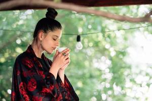 Shot of young woman drinking from tea bowl photo