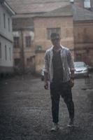 Portrait of carefree handsome young man is feeling free under the rain photo