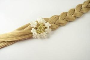 A blonde tress with a white flower on it lying on a white background photo