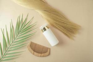 Blond hair and a hair serum and comb for extention lying on a beige background photo