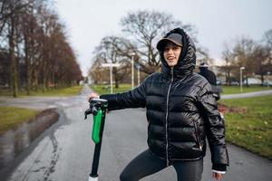 mujer en una chaqueta en un scooter eléctrico en un parque de otoño. foto