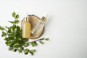 Two face serum or essential oil dropper bottles lying on a wooden plate in a cosmetology salon photo